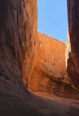 Narrow canyon walls of reddish sandstone towering under a clear blue sky