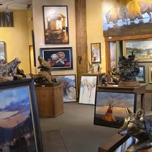 Gallery interior with various animal sculptures and framed paintings including buffalo, feathers, a teepee, and a train