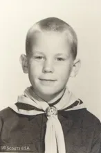 Young boy in a scout uniform with a neckerchief and a round emblem clasp