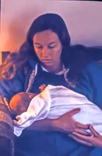 woman sitting and cradling a sleeping baby wrapped in a soft blanket