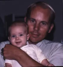 Man holding a smiling baby in a close embrace